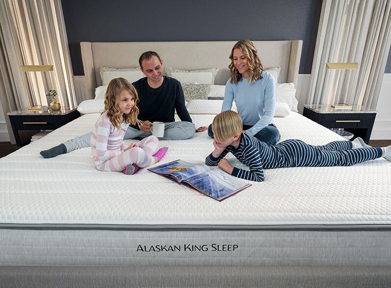 Shot of family sitting on Alaskan King mattress