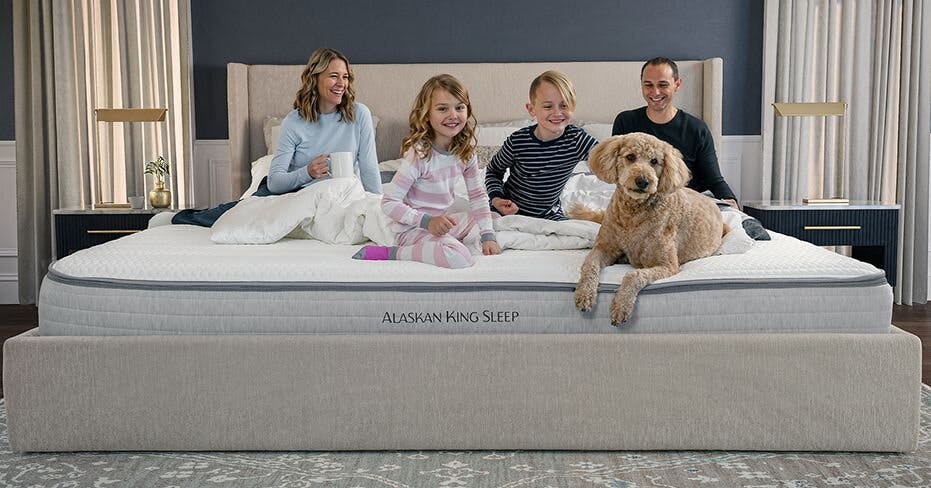 A family with kids and a dog lounging on an Alaskan king size bed